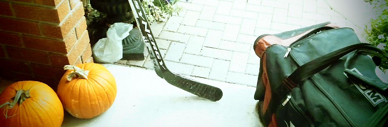 hockey bag and sticks beside some october pumpkins